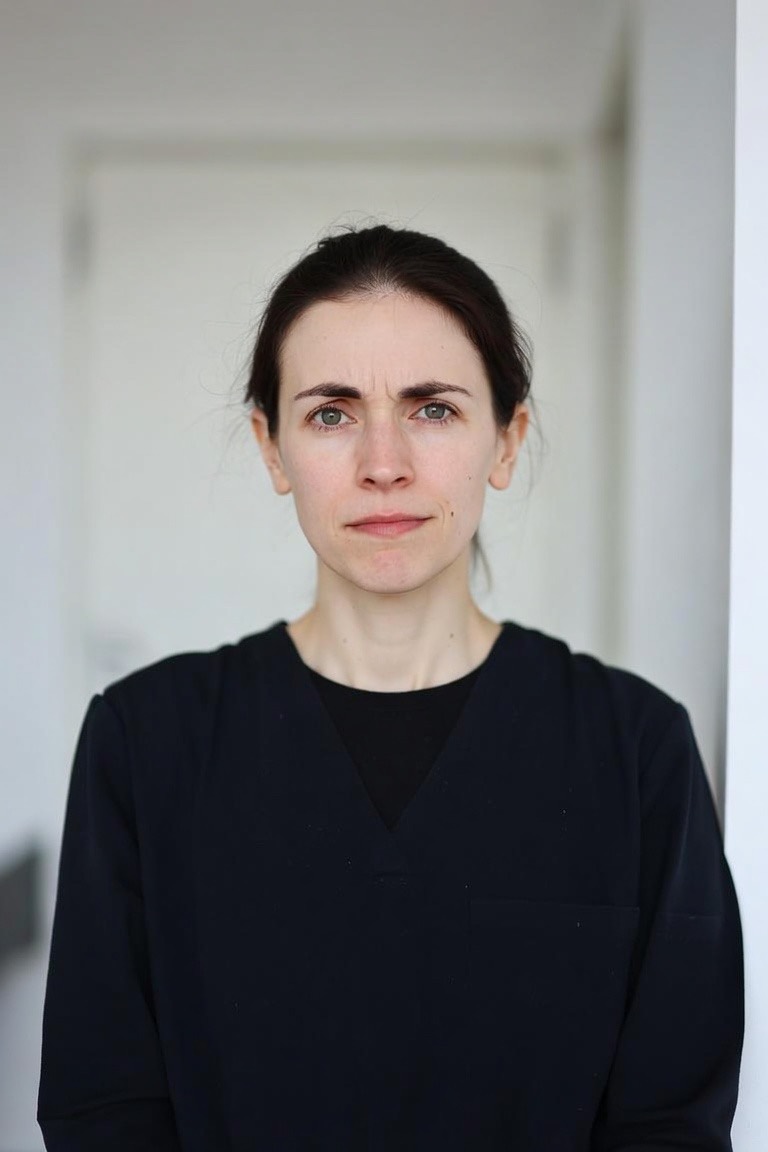 A physiotherapist in dark scrubs looking straight into the camera, shot in the same way as every other portrait in the series.